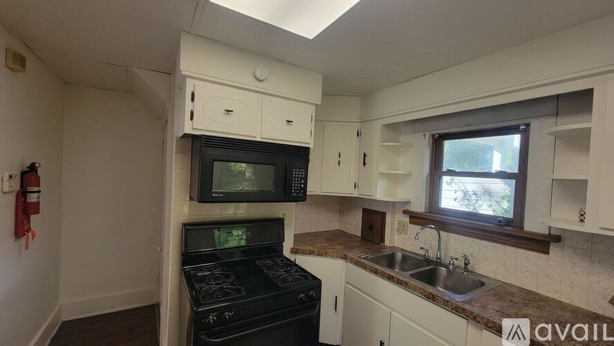A kitchen with a stove, microwave, and sink.