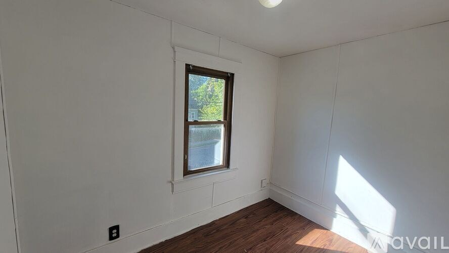 A room with a window and wooden flooring.