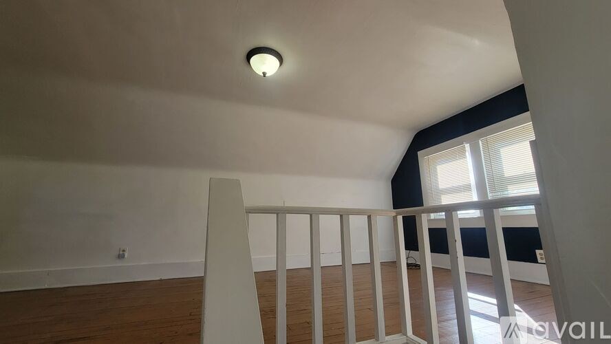 A room with a white chair and a window with blinds.