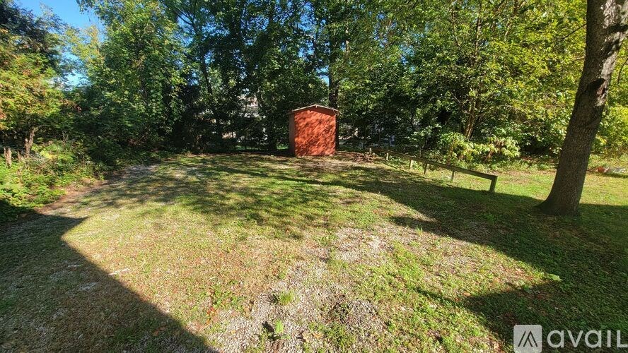 A red barn sits in a field with trees in the background.