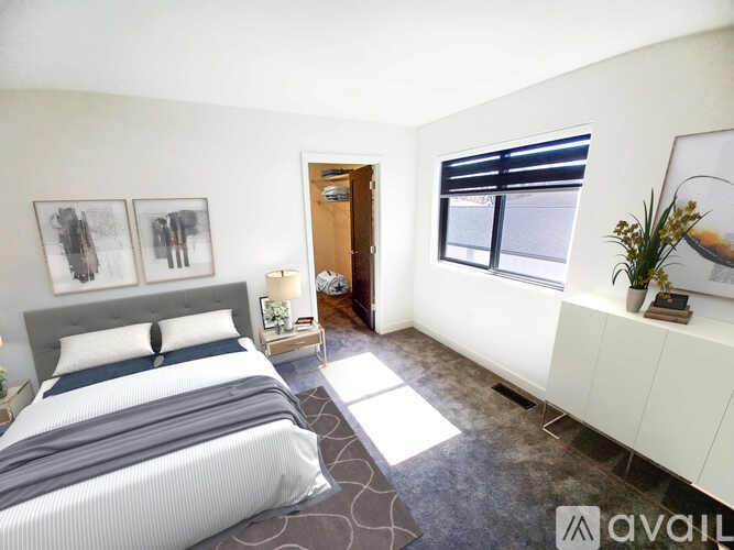 A bedroom with a large bed and a window with blinds.