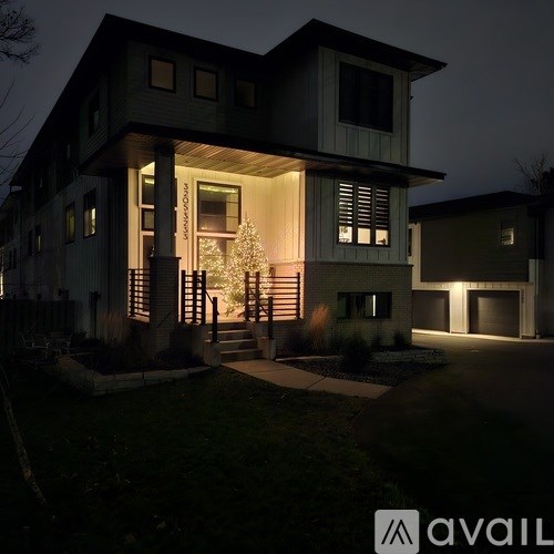 A house with a lit up Christmas tree in the front yard.