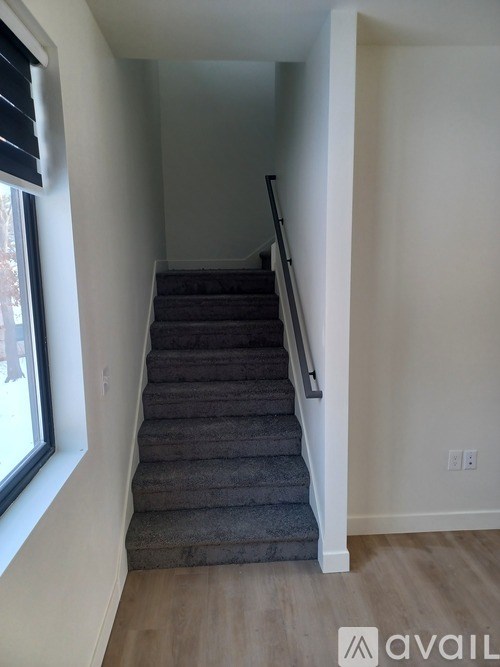 A staircase with a carpeted runner and a metal handrail.