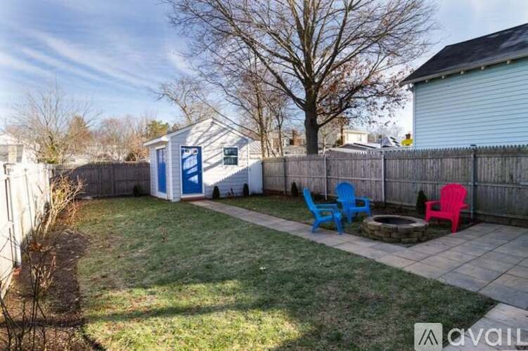 A backyard with a white fence and a blue and pink chair.