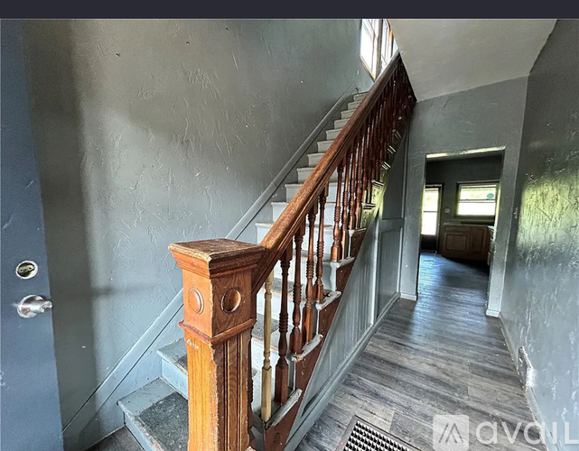 A staircase with a wooden handrail and a metal grate on the floor.