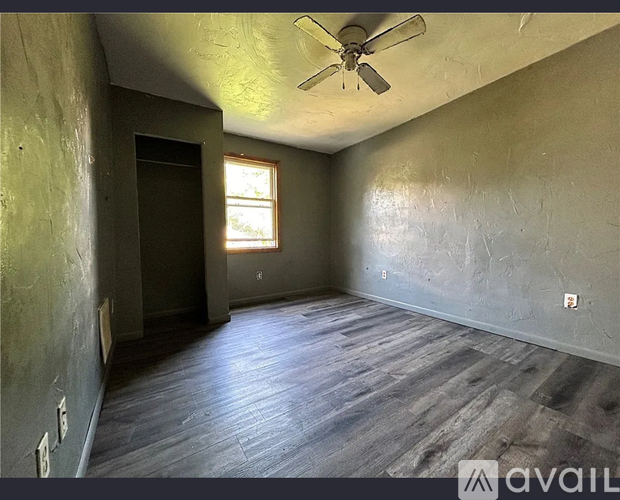 A room with a ceiling fan and wooden flooring.