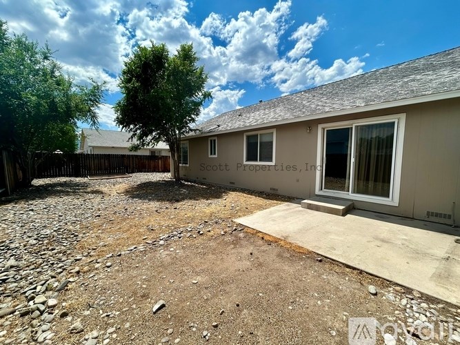 A backyard with a tree and a house with a sign that says "Scotts Property, Inc."