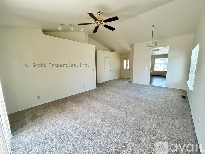 A spacious room with a ceiling fan and carpeted floor.