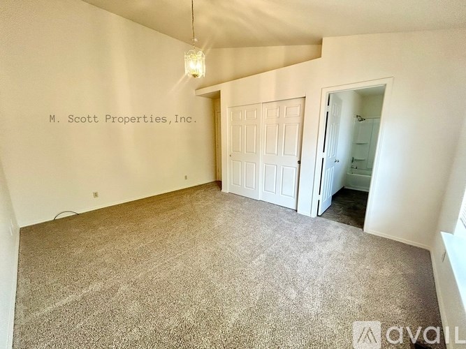 A carpeted room with a doorway leading to another room.
