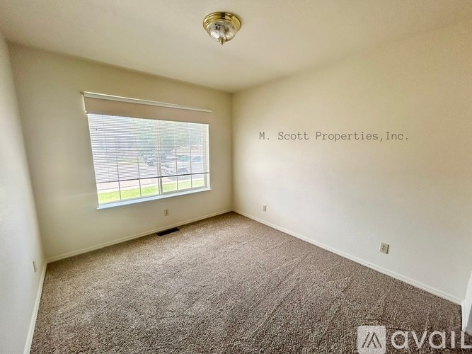 A carpeted room with a window and a ceiling light.