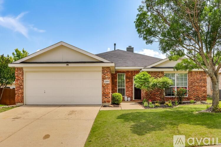 A house with a garage and a tree in front.