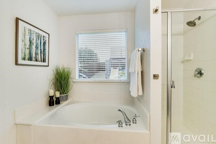 A bathroom with a white tub and a window with blinds.