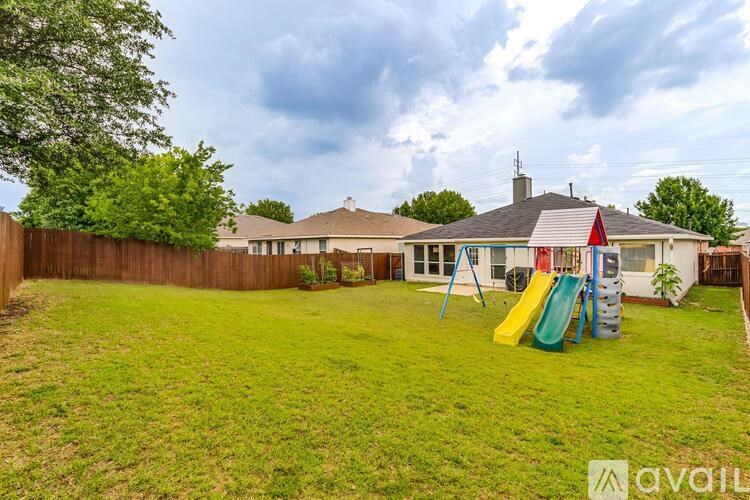 A backyard with a playground and a house in the background.