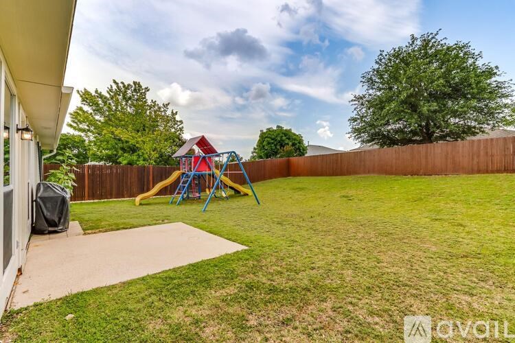 A backyard with a playground and a wooden fence.