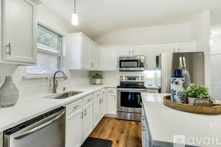 A modern kitchen with white cabinets and stainless steel appliances.