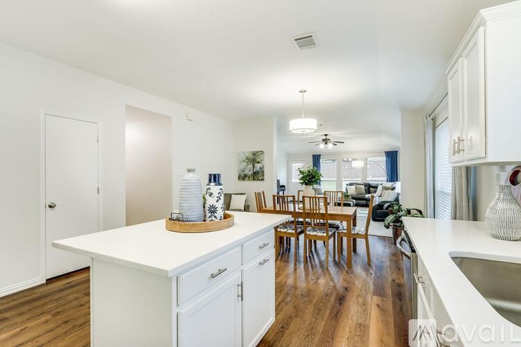 A kitchen with white cabinets and a wooden floor.