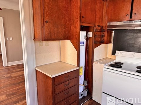 A kitchen with a white stove and wooden cabinets.