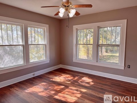 A room with a ceiling fan and three windows.