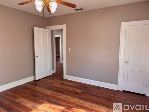 A room with a ceiling fan and wooden flooring.