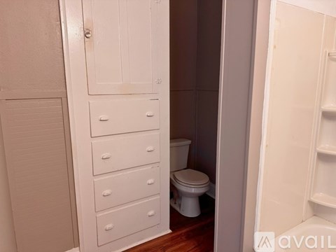 A white bathroom with a toilet and drawers.