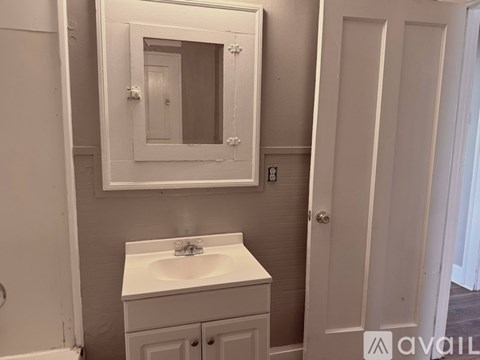 A white sink is in a white cabinet under a mirror in a bathroom.