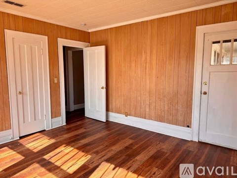 A room with wooden walls and floors, and three doors.