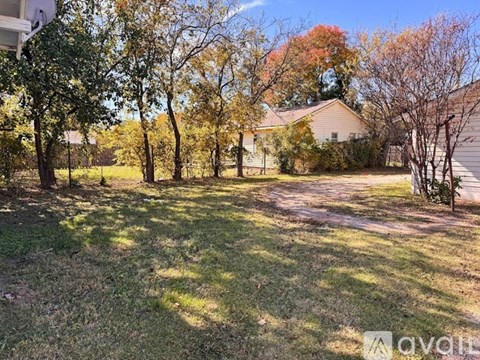 A backyard with a house, trees, and a clear sky.