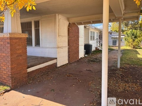 A porch with a brick pillar and a white wall.