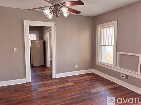 A room with a ceiling fan and wooden floors.