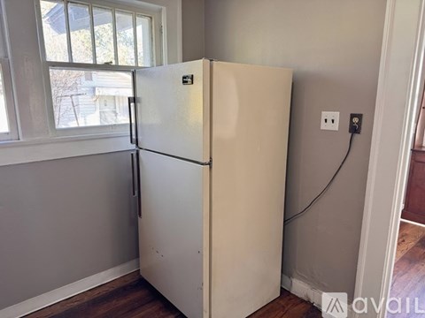 A white fridge in a room with a window.