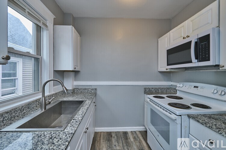 A kitchen with a sink, stove, and microwave.
