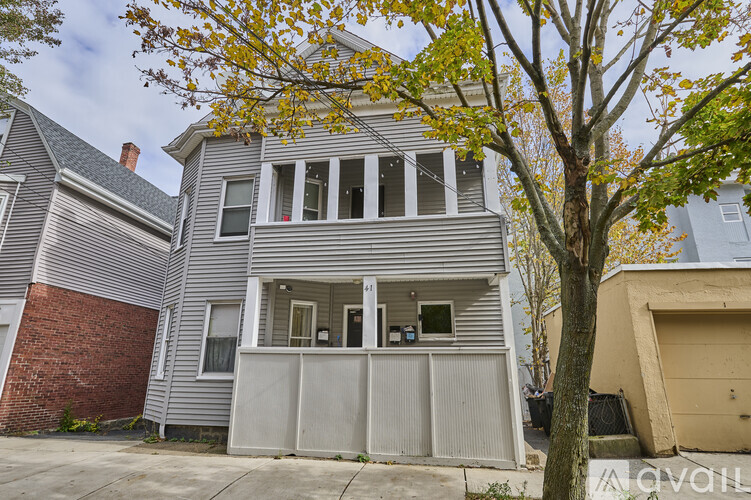 A grey house with a tree in front of it.
