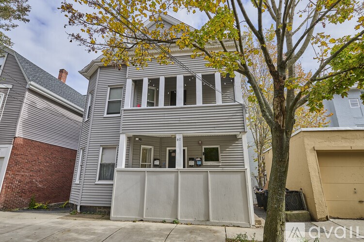 A grey house with a tree in front of it.