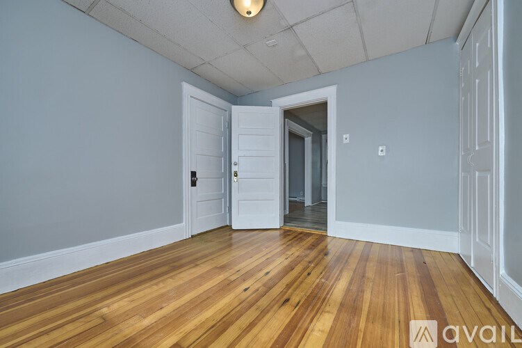 A room with wooden floors and two doors, one of which is open.