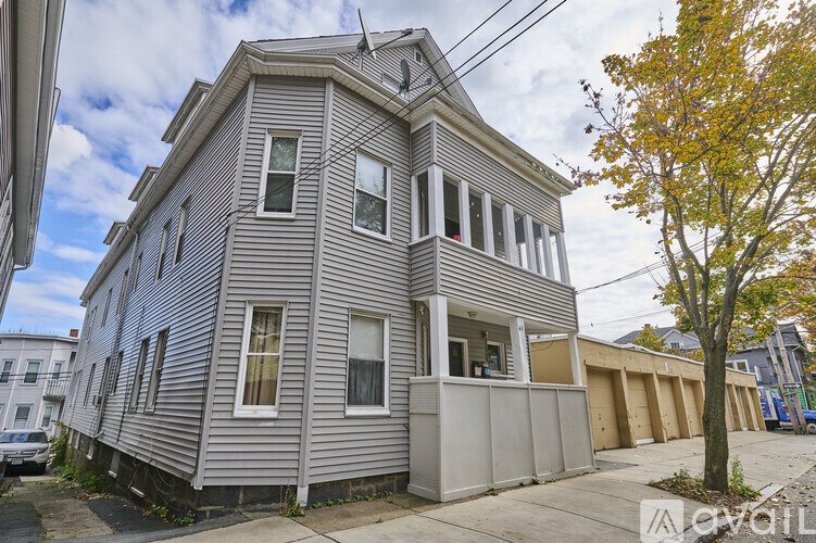 A grey two-story house with a tree in front.