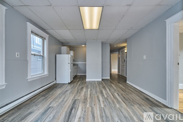 A spacious room with wooden flooring and white walls.