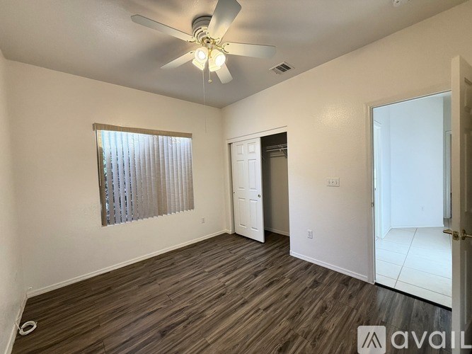 A room with a ceiling fan and a window with blinds.