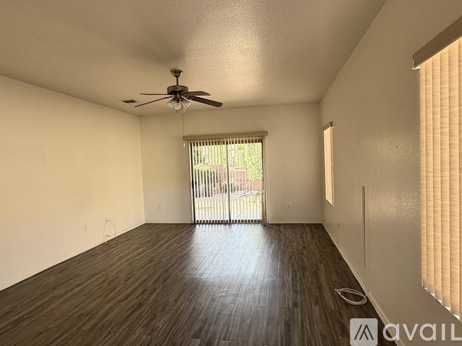 A room with a ceiling fan and sliding glass doors leading to a balcony.
