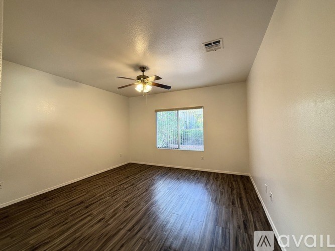A room with a ceiling fan and wooden flooring.