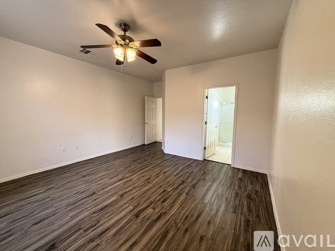 A room with a ceiling fan and wooden flooring.