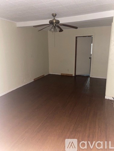 A room with a ceiling fan and wooden flooring.