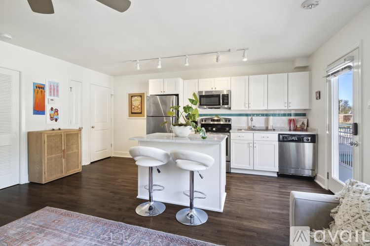 A kitchen with white cabinets and a bar area with stools.
