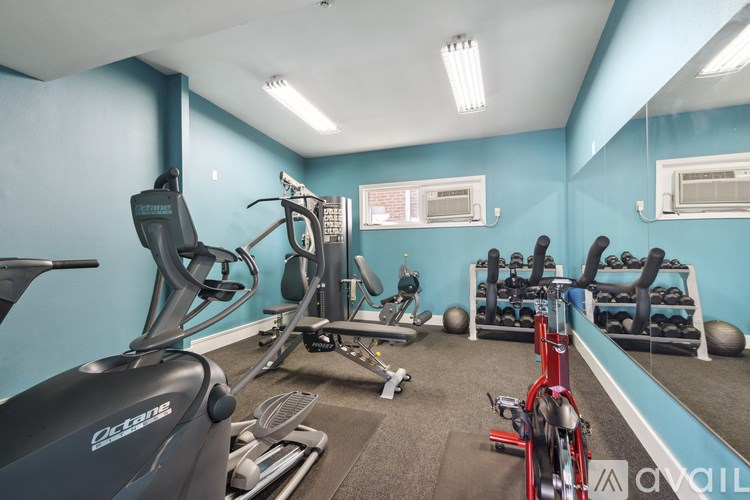A gym with a variety of equipment including a stationary bike, a treadmill, and a rowing machine.