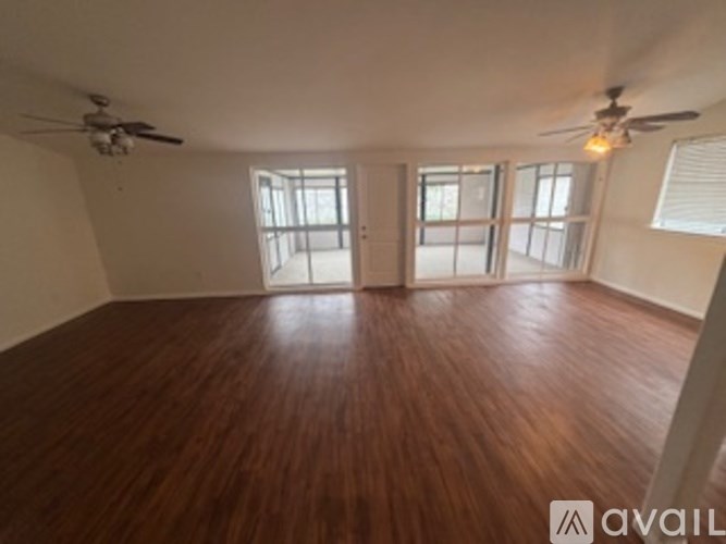 A room with wooden flooring and ceiling fan.