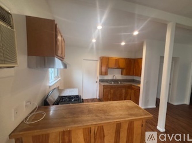 A kitchen with wooden cabinets and a wooden island in the middle.