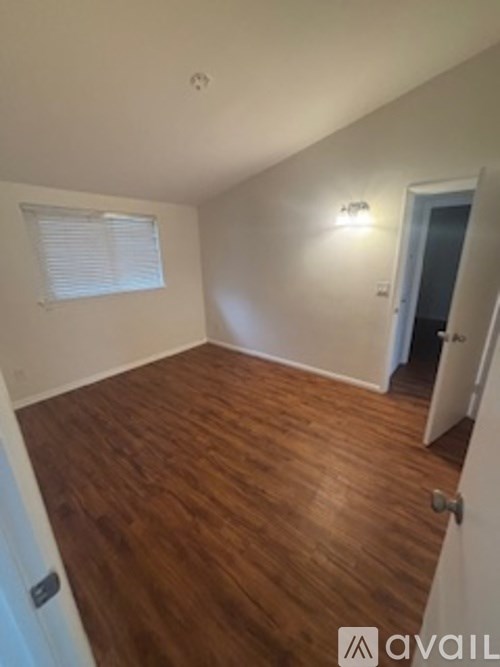 A room with wooden floors and a window with blinds.