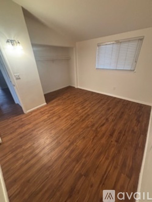 A room with wooden flooring and a window with blinds.