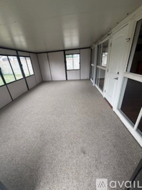 A caravan interior with a grey carpet and white cupboard doors.