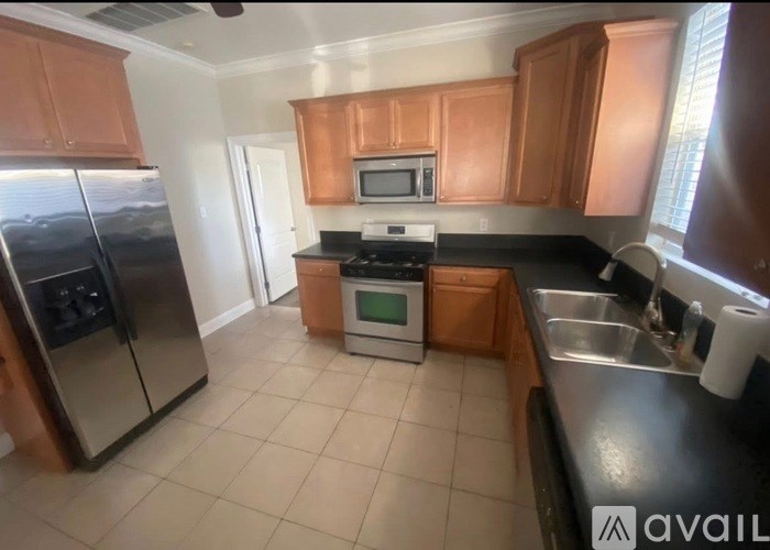 A kitchen with a refrigerator, microwave, oven, and sink.