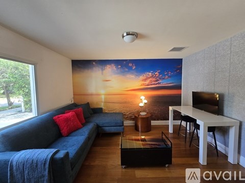 A living room with a large sunset mural on the wall.